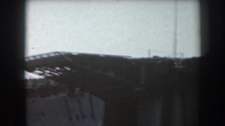 Distant 8mm frame of a grey naval vessel's deck edge and low superstructure under clear California daylight.