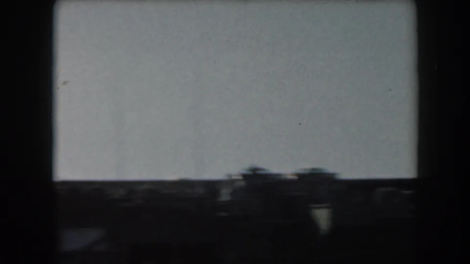Soft 8mm view of dark maritime structures along the lower frame, likely part of the same naval vessel or dock area.