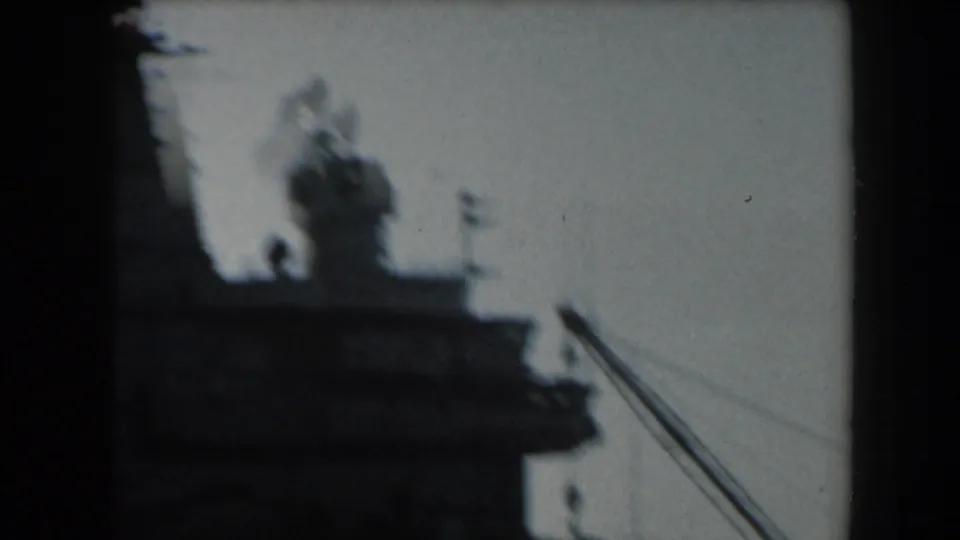 1961 California frame showing blurred naval superstructure, mast-like details, and diagonal industrial lines near the dockside view.