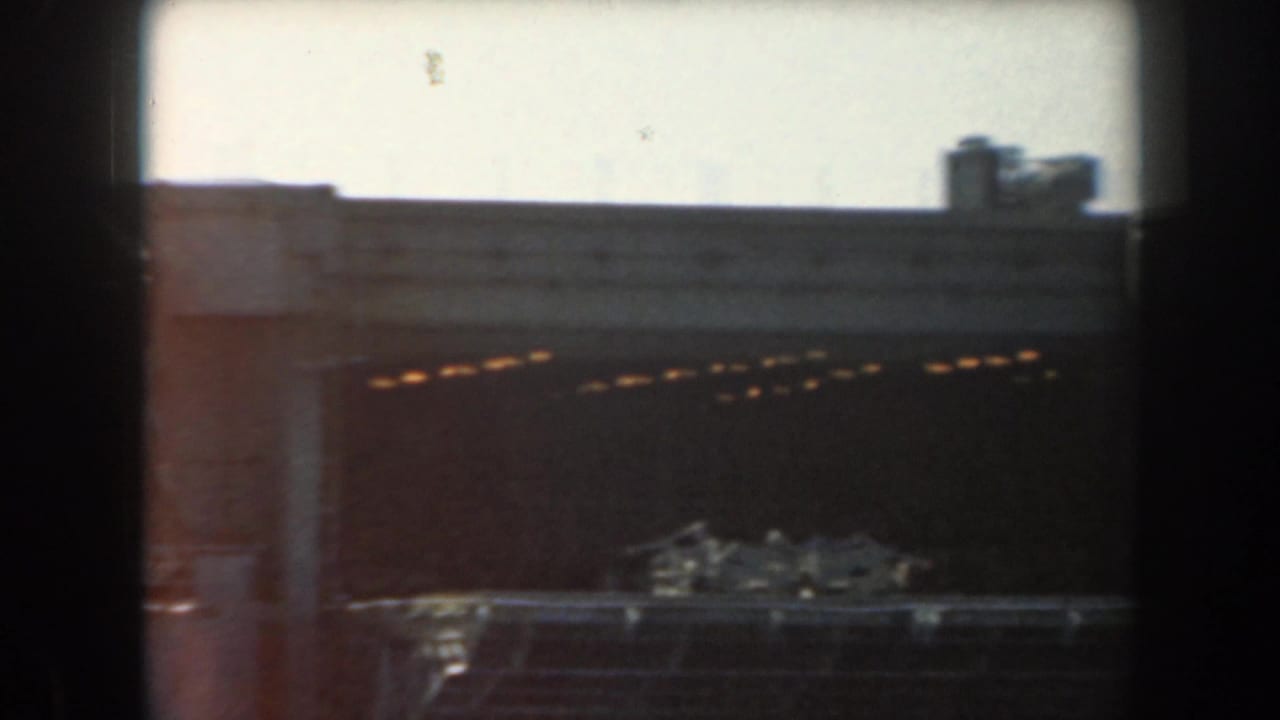 Dim tunnel wall with warm lights and dark framing around the film gate.