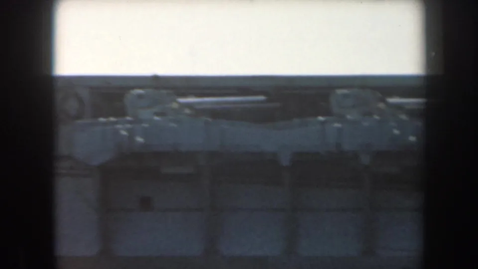 Soft 1961 California 8mm frame with a pale tunnel-side structure, a crane-like arm or pipe, and dark shadowed areas below.