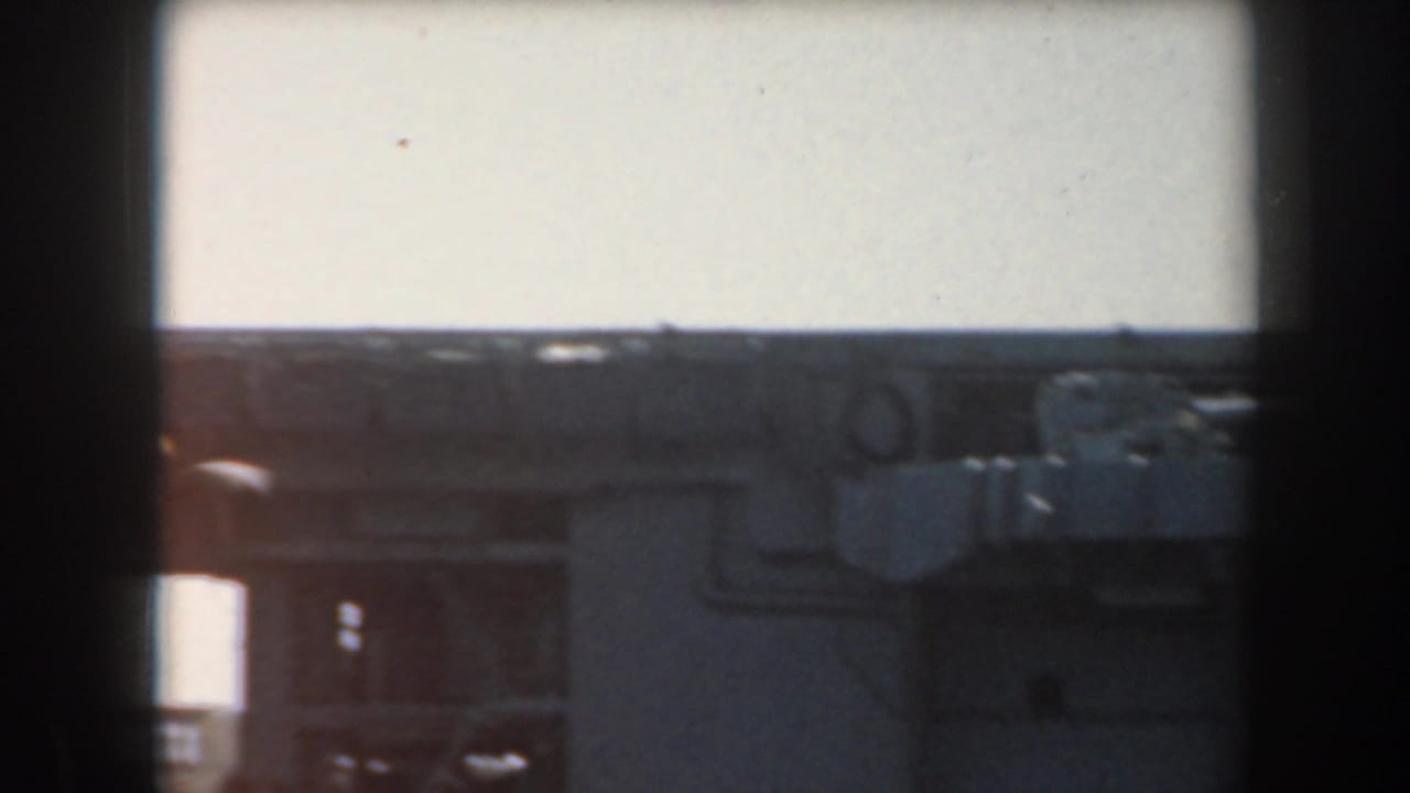 Dark battleship structure seen against a bright sky through a soft 8mm frame.