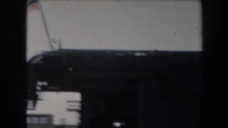 A hazy 8mm view of the battleship's upper structures and deck edge in bright California daylight.