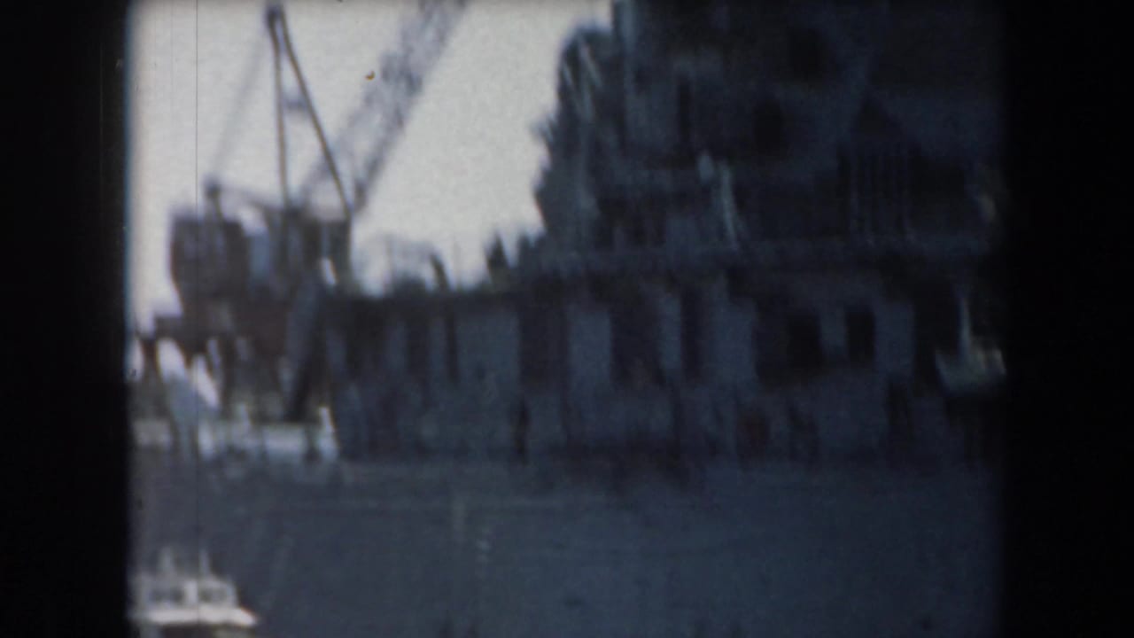 Warship superstructure and crane seen across harbor water.