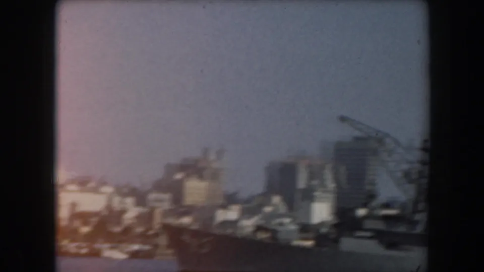 Soft, slightly overexposed 1961 California harbor view with cranes, waterfront buildings, and city skyline.