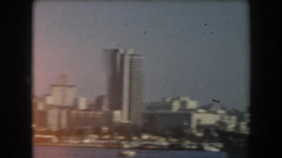 1961 California waterfront view with tall white high-rises and low harbor buildings seen across the water.