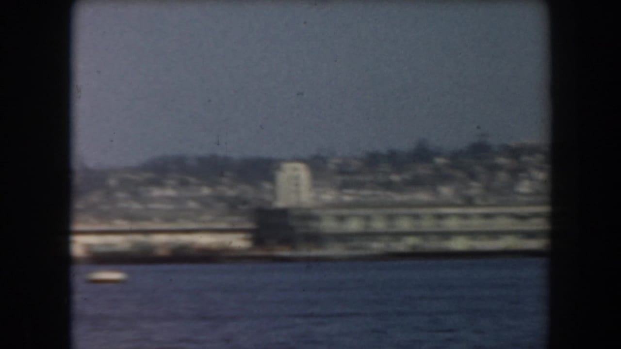 1961 California 8mm view of blue water with a soft distant shoreline and buildings beyond the waves.