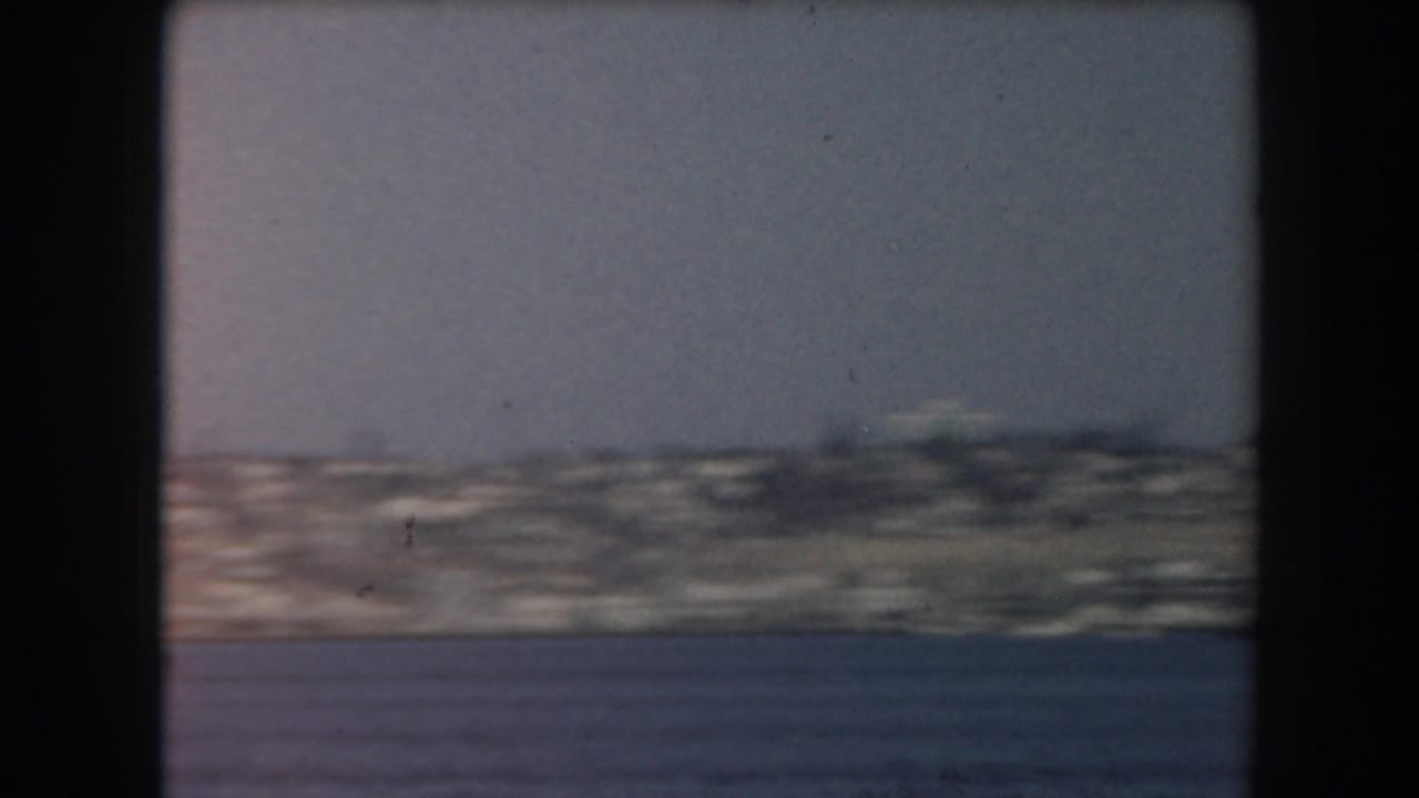 Open water with a distant low shoreline under a clear sky.