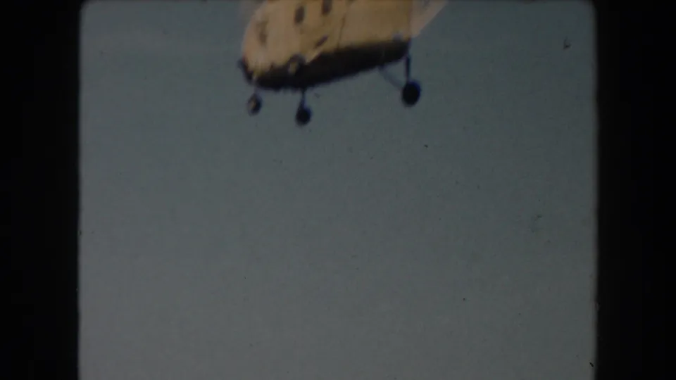 1961 California 8mm frame showing a yellow helicopter partly cropped at the top of a pale sky.