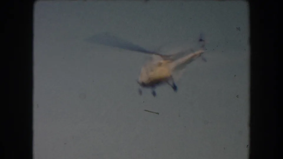 1961 California 8mm frame with a blurred yellow helicopter moving through the sky.