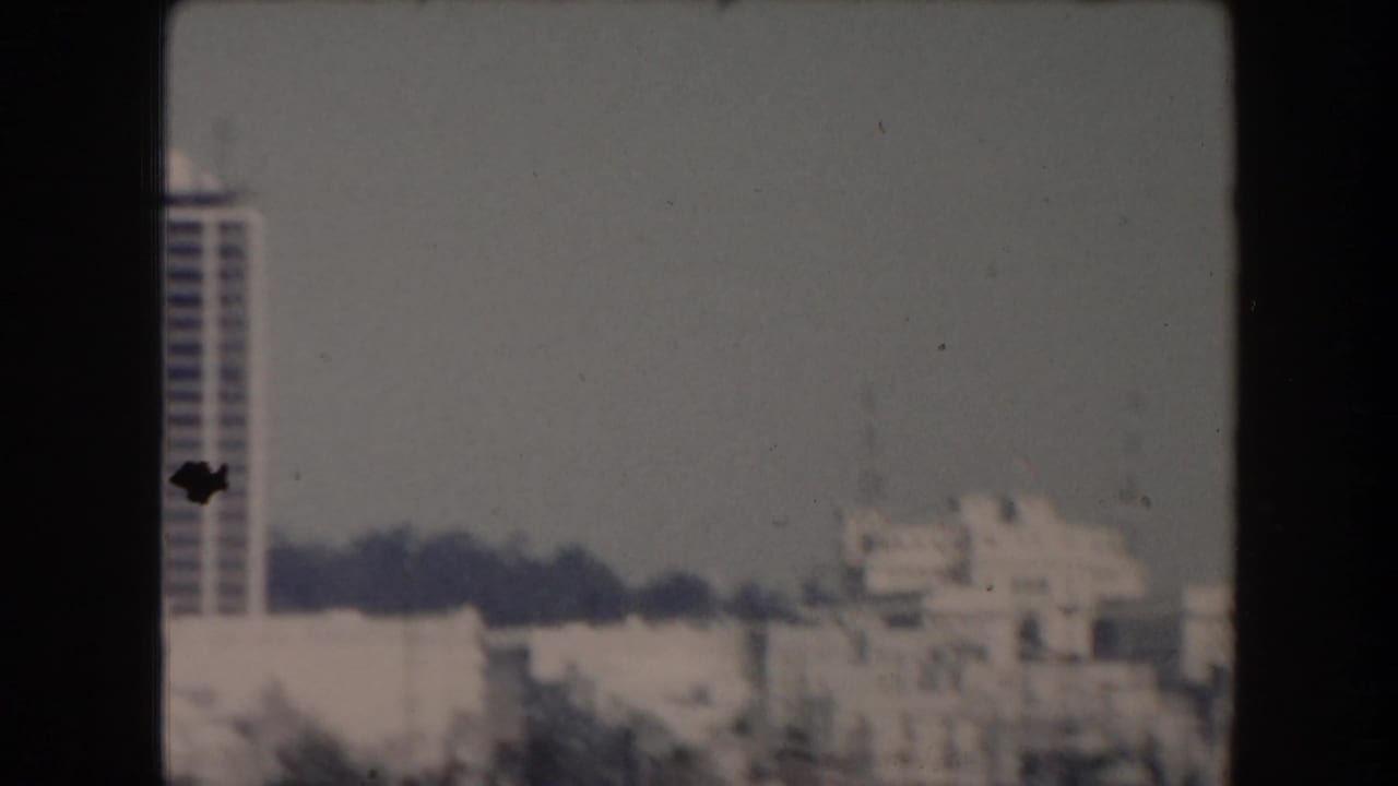 Soft 8mm view of waterfront buildings with a tall tower at the left edge.