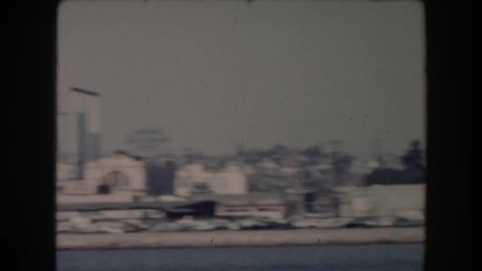 Hazy 1961 California waterfront view with low buildings, a tower-like structure, and open water in the foreground.