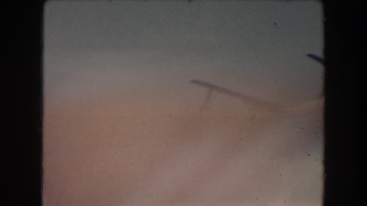 Soft, mostly blank 8mm frame with faded sky tones and film edge darkness.