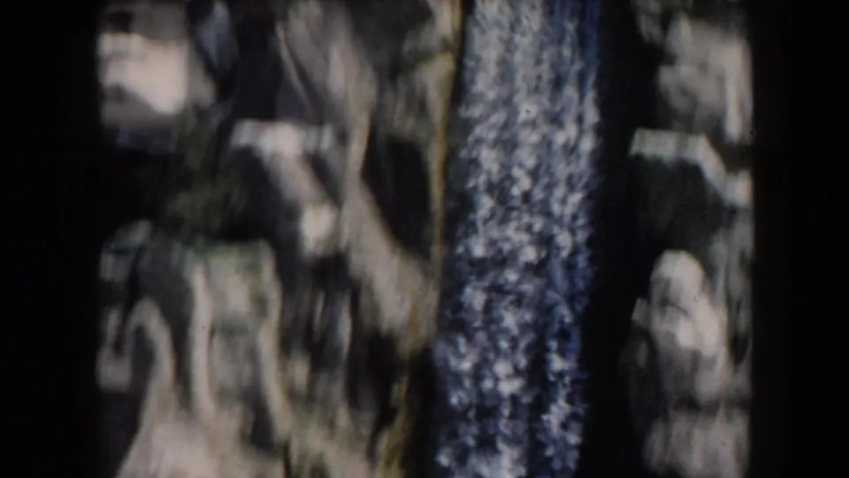 Visitor-shot 8mm view of a rugged waterfall area in California, with dark vertical shapes and rocky cliff texture.