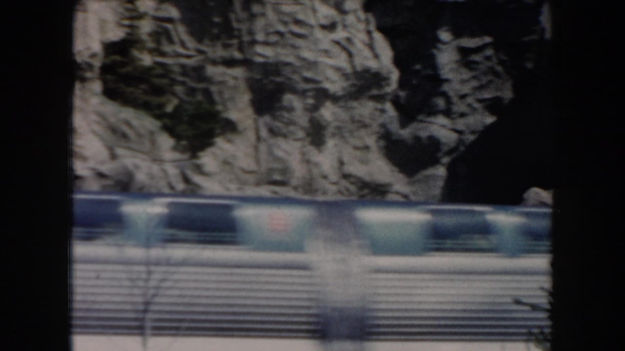 Blurred monorail cars moving past a rocky canyon backdrop.