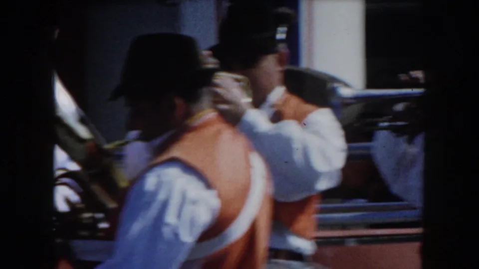 Band members wearing dark hats and orange vests play brass instruments in a handheld California 1961 home-movie frame.