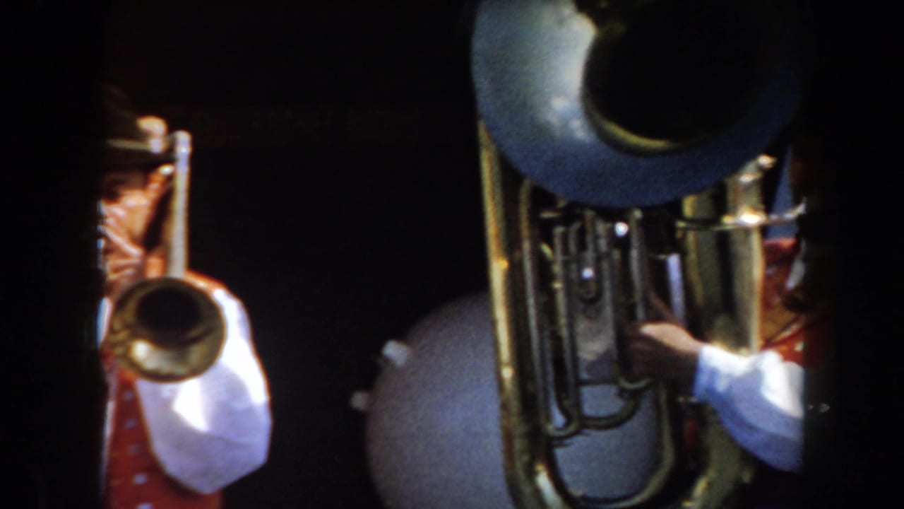 1961 California 8mm frame showing brass musicians in traditional German-style attire, with a large tuba bell near the center.