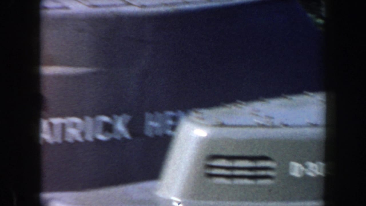 Close view of a gray vessel side with partial PATRICK lettering and deck hardware.