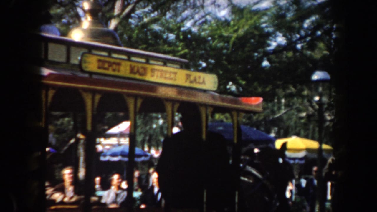 1961 California amusement park trolley with Depot Main Street Plaza signage, shaded riders, trees, and outdoor seating visible in soft 8mm color.
