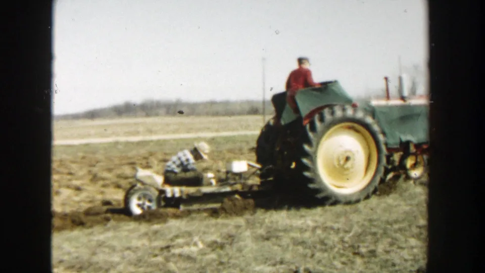 Near the end of the clip, the Wisconsin Dells farm scene shows the tractor, operator, and worker aligned across the open field.