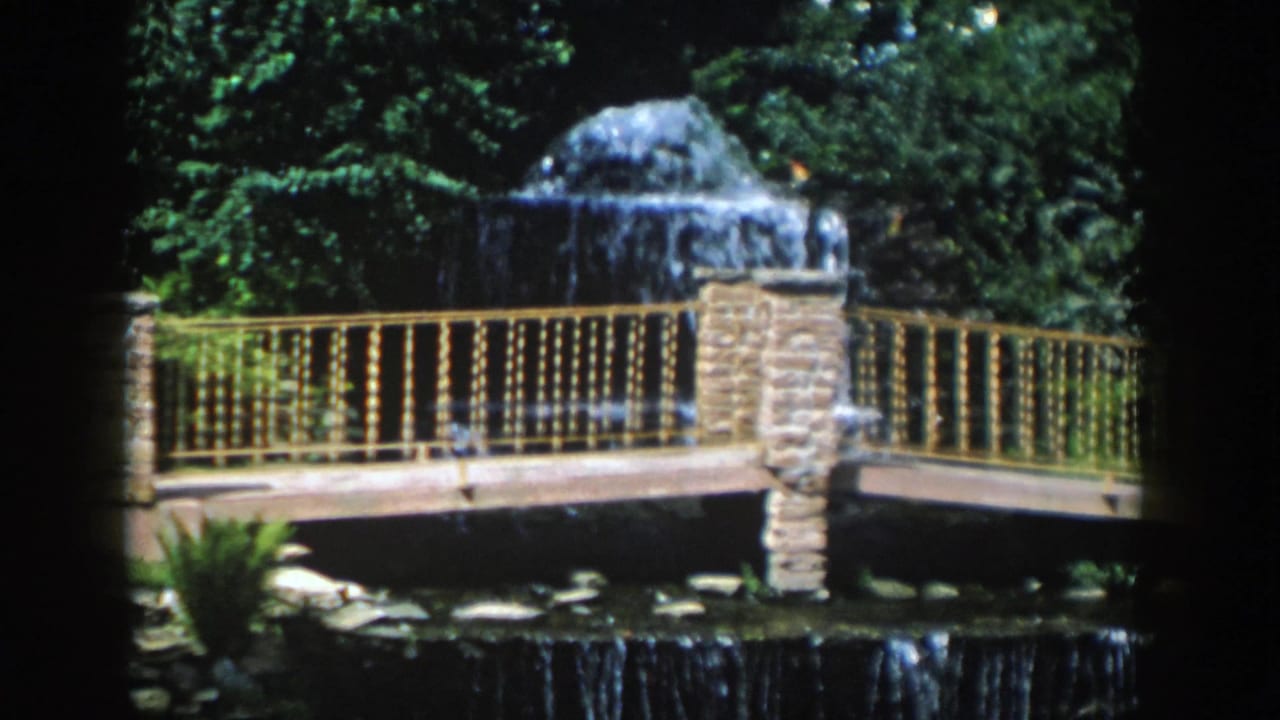 Water cascades from a domed fountain behind a bridge with ornate railings.