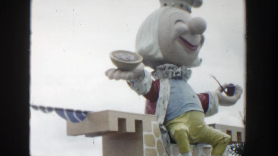1954 Wisconsin Dells frame with a crowned puppet display, pipe and bowl visible, seen through soft 8mm home-movie framing.