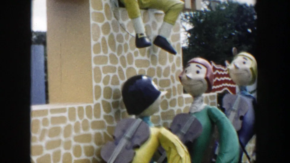 1954 Wisconsin Dells frame showing the large crowned puppet over several smaller painted puppets beside the faux-stone display.