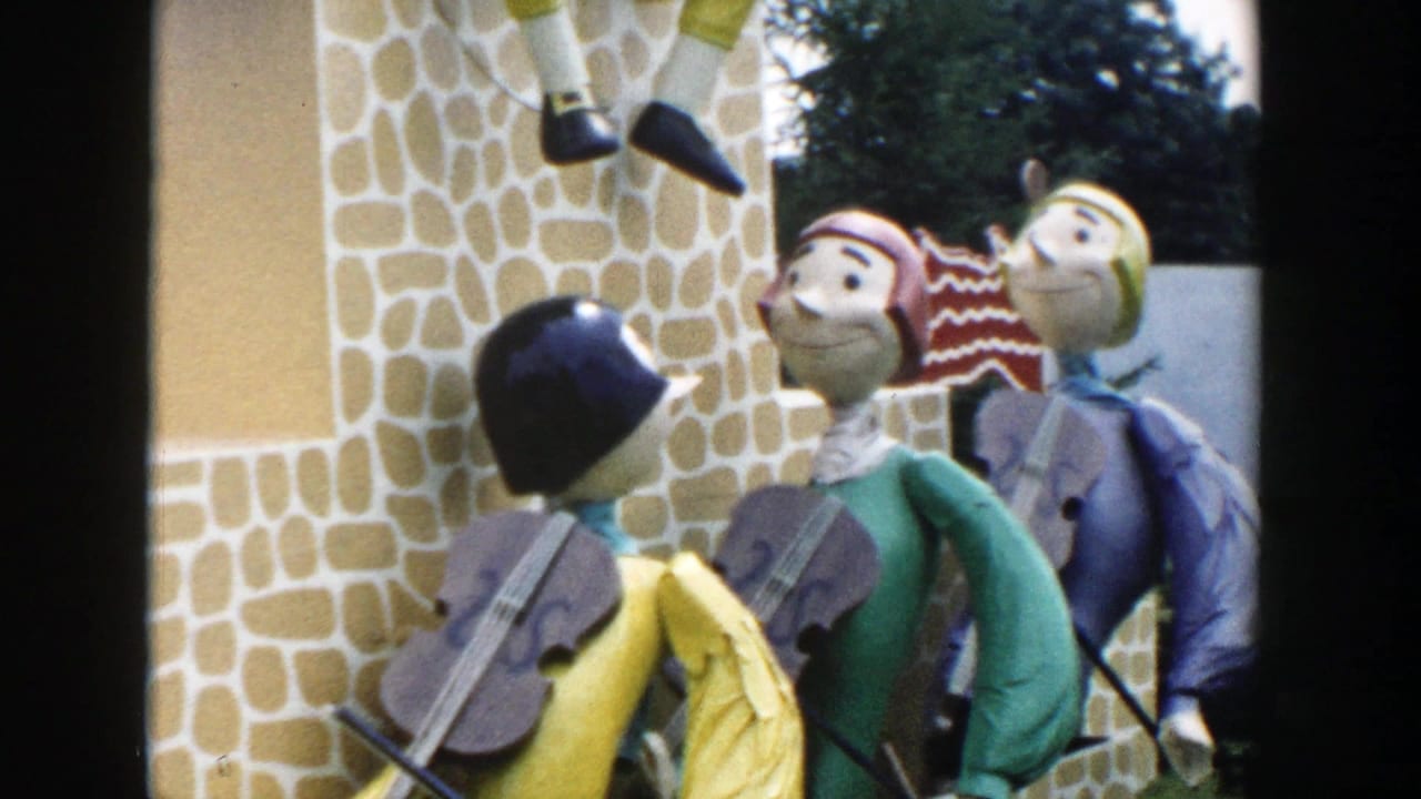 1954 Wisconsin Dells home-movie frame showing colorful decorative figures with violins near a stone-patterned facade.