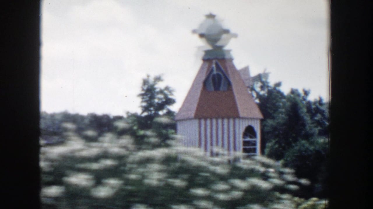 1954 Wisconsin Dells 8mm frame showing a decorative red-roofed gazebo-like structure in a landscaped park setting.
