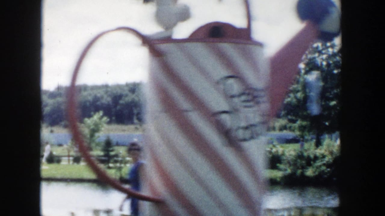 Decorative pitcher form in the foreground overlooks a landscaped Wisconsin Dells pond area with trees and tourists in the distance.