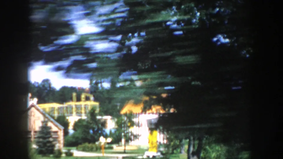 A visitor-shot view of Wisconsin Dells fantasy architecture, with yellow painted structures, trees, and landscaped grounds in 1954 footage.