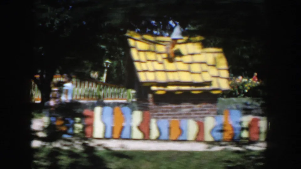 Close visitor view of a strange house facade at the Wisconsin Dells attraction, showing painted vertical stripes and a globe-topped roof detail.