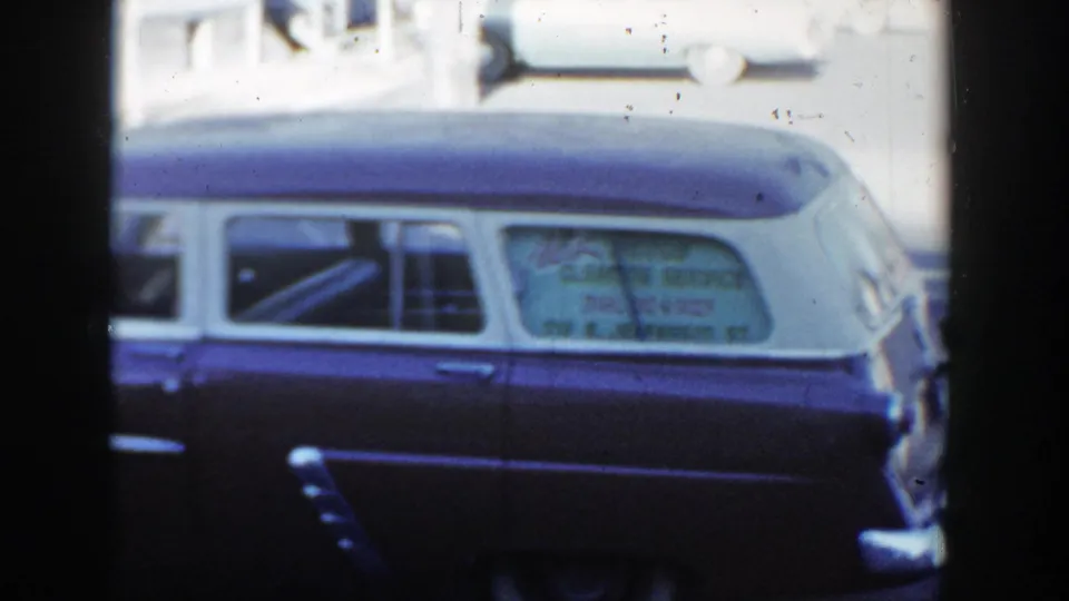 1954 Wisconsin Dells street view showing a dark blue and white station wagon with service lettering in the rear window.