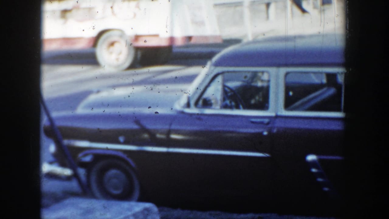 1954 Wisconsin Dells 8mm frame showing a dark two-tone station wagon with chrome trim parked along a street.