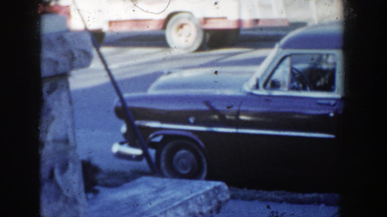 Parked vintage station wagon with a white-and-red truck visible across the street.