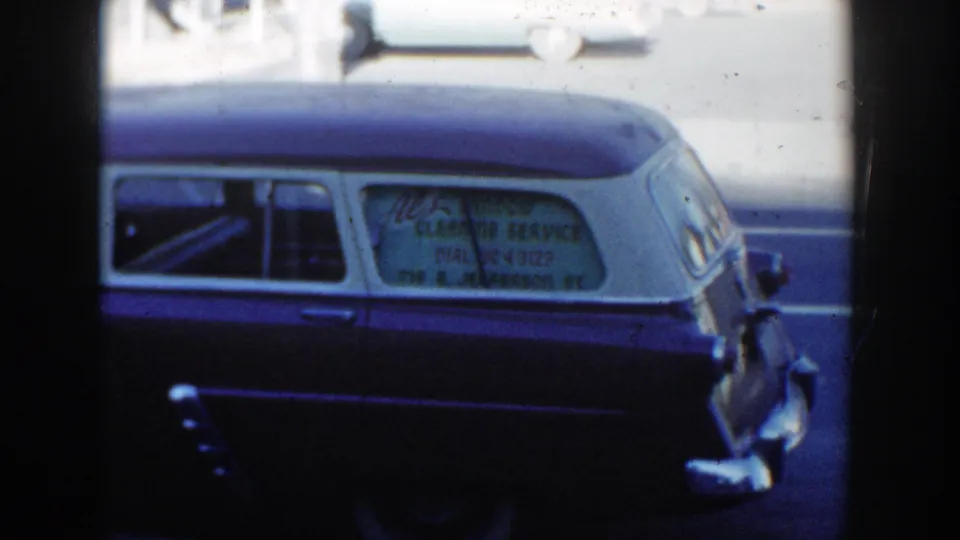1954 Wisconsin Dells 8mm frame showing rear-window lettering for Al's Window Cleaning Service on a parked station wagon.