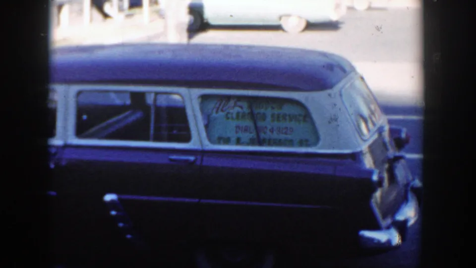 Wisconsin Dells 1954 home-movie frame of a two-tone station wagon with visible window-cleaning service lettering.