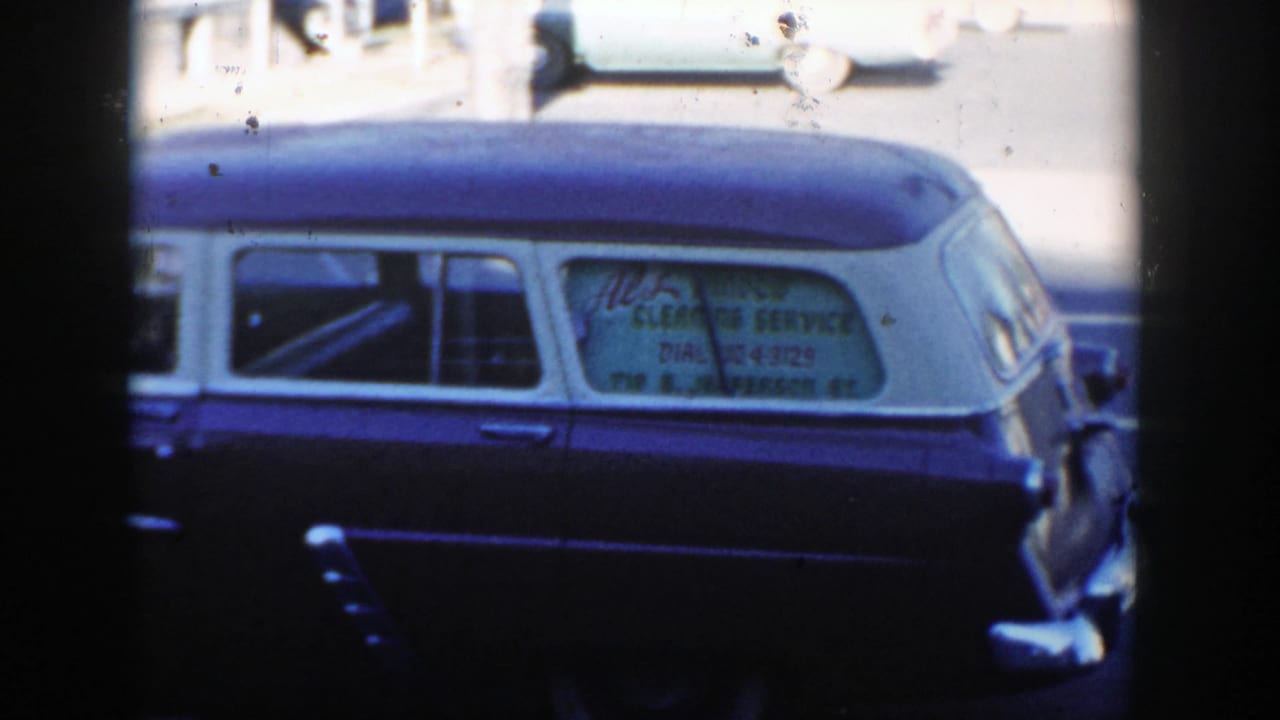 Dark blue vehicle with white roof parked beside a street, partly obscured by dark frame edges.