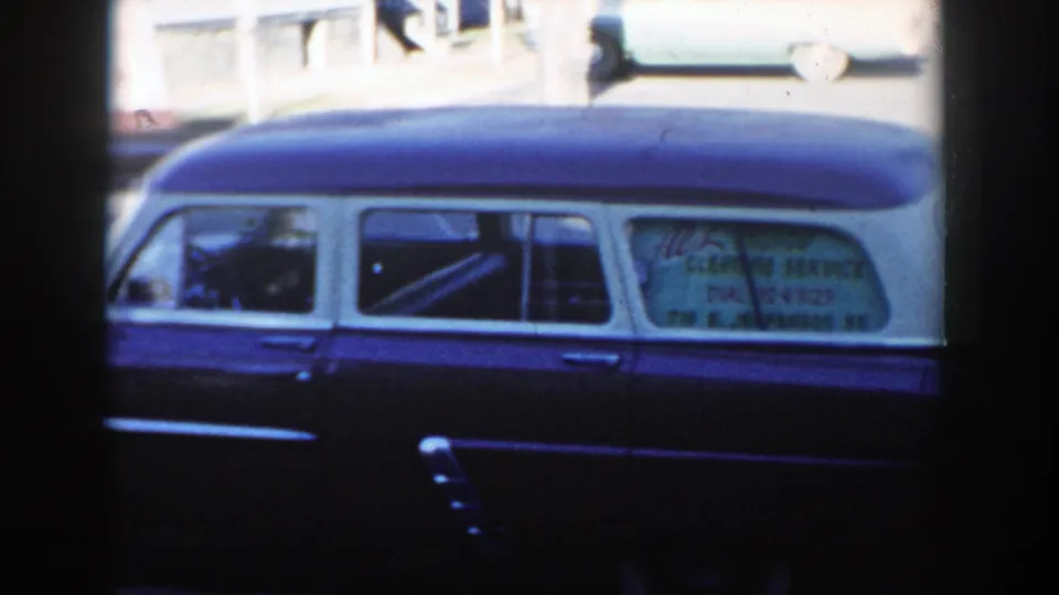 The pan holds on the two-tone vehicle in Wisconsin Dells, with window lettering for a local service business visible but soft.