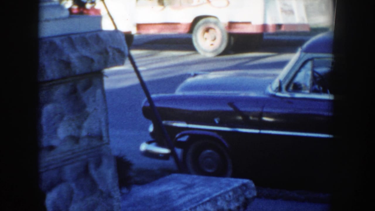 Dark station wagon partly seen through a window or porch frame beside a stone wall.