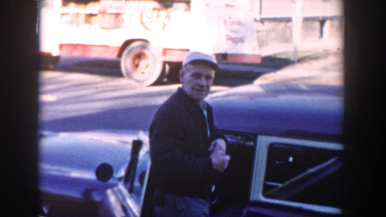 In Wisconsin Dells, 1954, a man in a cap stands by an open vintage car door with a Pepsi truck in the background.