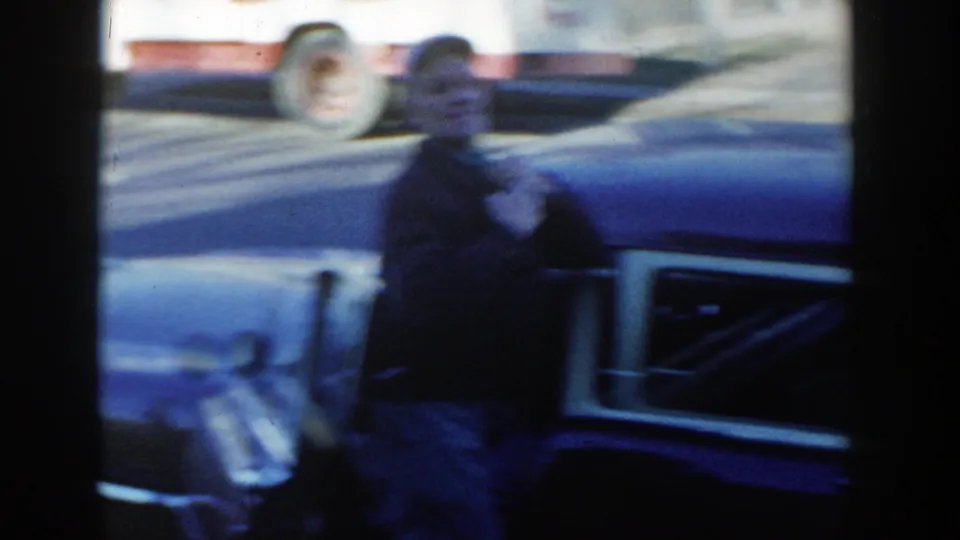 A soft, handheld frame shows the man moving beside the open vintage car door during the Wisconsin Dells street moment.