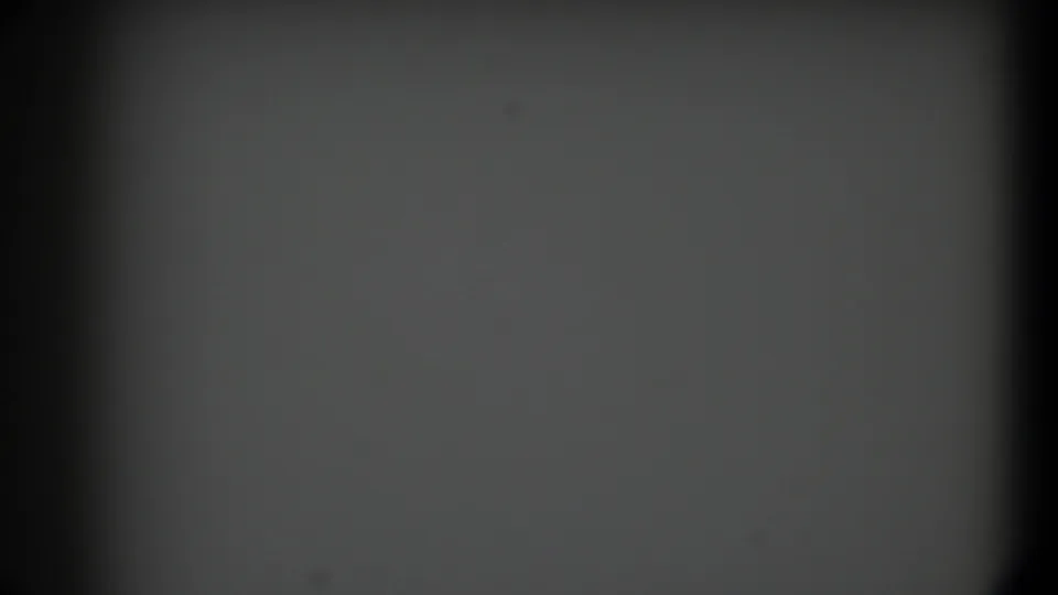 1958 Texas 8mm frame with an empty gray field, dark rounded gate edges, faint grain, and scattered dust specks.