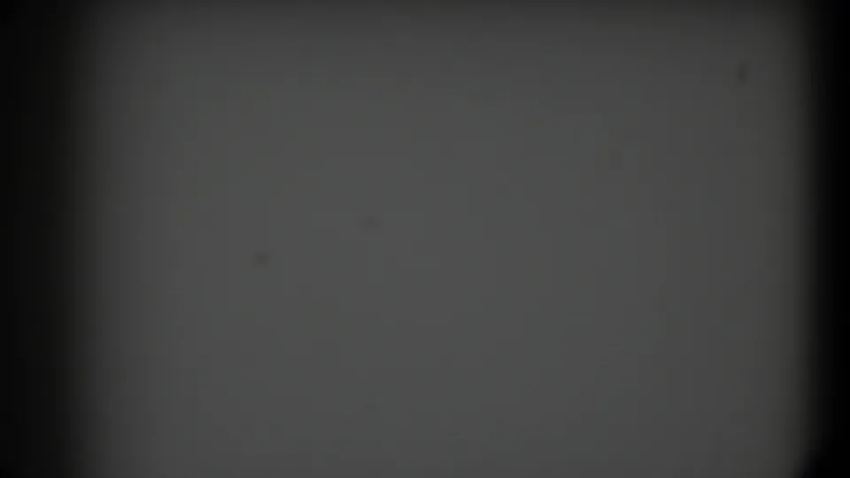 Soft, mostly gray 8mm frame with a dark vertical gate edge and visible grain from the 1958 Texas footage.