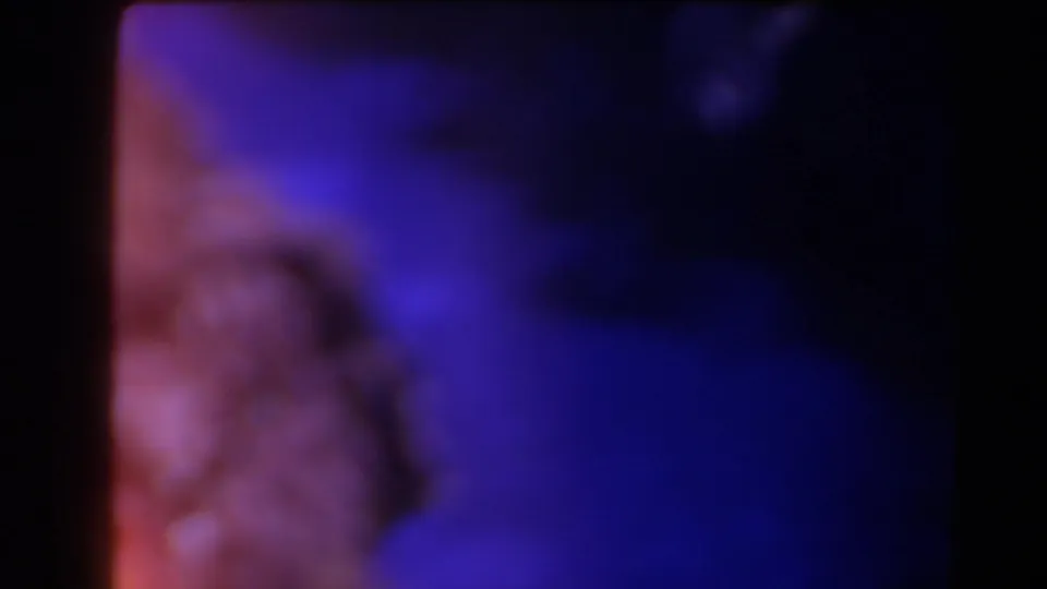 1958 Texas home-movie frame with a blurred rock shape, saturated blue-purple tones, and visible 8mm frame edge.