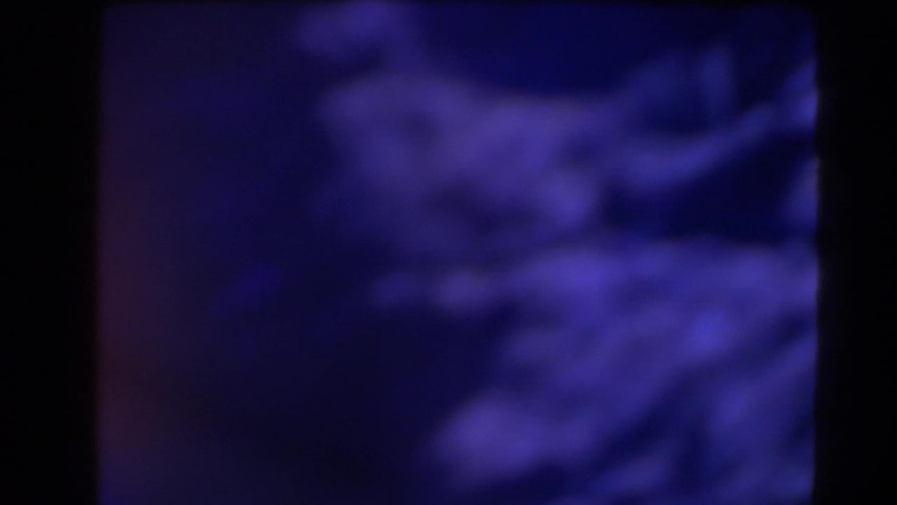 1958 Texas 8mm frame with a blurred blue-purple coastal or rocky view partially obscured by dark frame divisions.