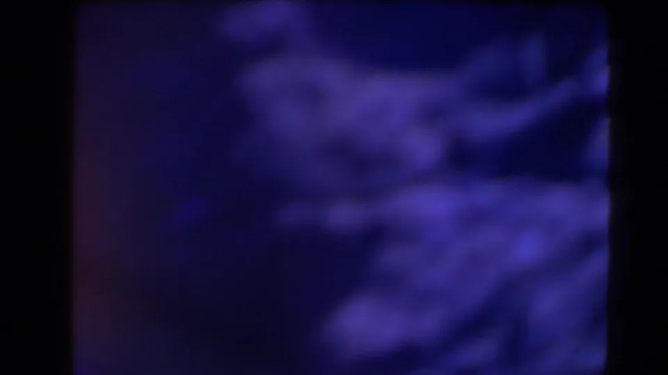 1958 Texas 8mm frame with a blurred blue-purple coastal or rocky view partially obscured by dark frame divisions.