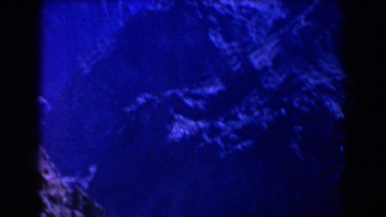 1958 Texas 8mm frame showing blue-tinted mountain slopes, rocky forms, dark shadows, and soft film grain.