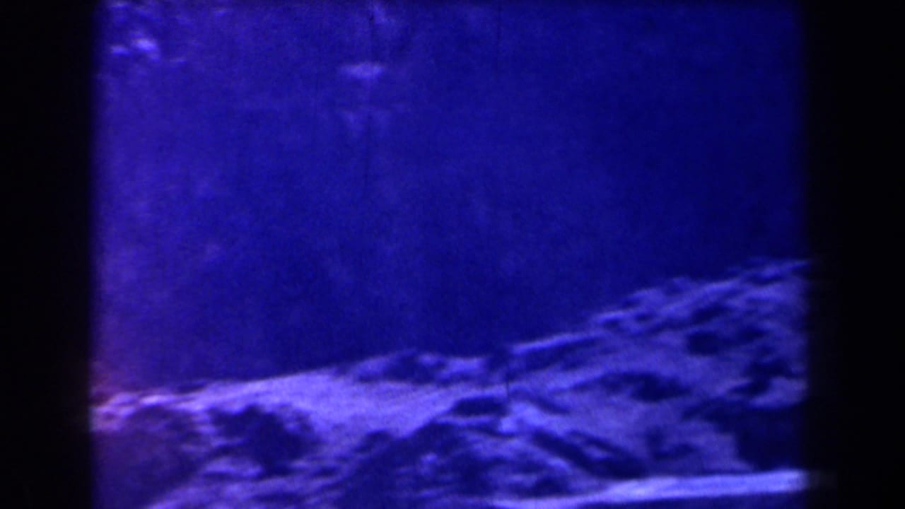 Blue-tinted rocky slope framed by dark film edges.