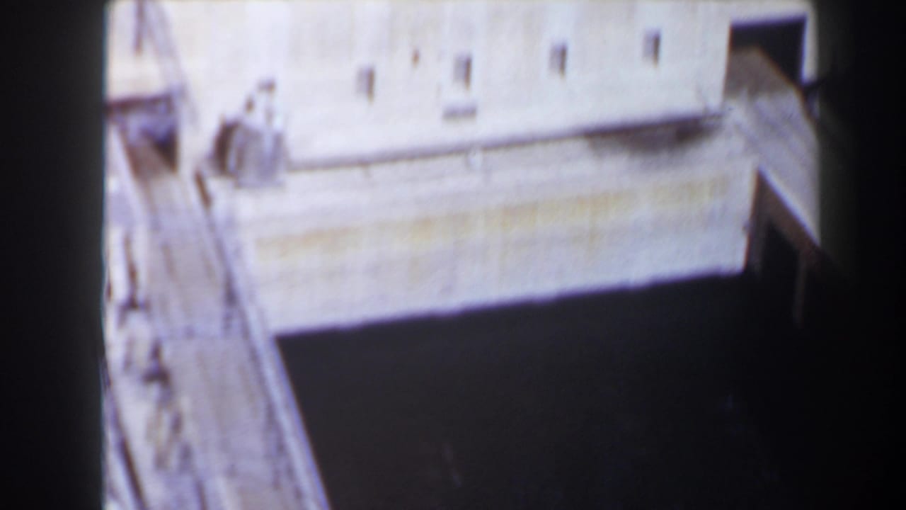 1958 Texas home-movie frame showing a close, high-angle view of the Max Starcke Dam concrete structure and dark channel below.